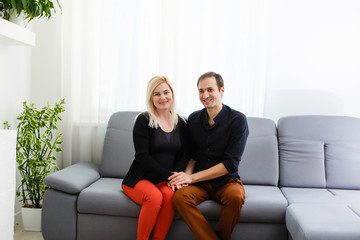 Obraz premium Happy young couple is hugging and smiling while sitting on the couch at the psychotherapist.