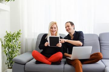 Cheerful couple searching something on laptop at home