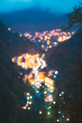 Obraz na płótnie Canvas Borjomi, Samtskhe-Javakheti, Georgia. Abstract Blurred Bokeh Boke Background Of Evening Borjomi Cityscape And Central Park In Night Illuminations Lighting
