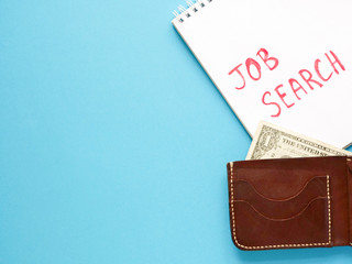 notebook with job search phrase, brown wallet, one dollar on blue background. looking for a work, last money, poverty, unemployment, job loss concept. Flat lay, copyspace.