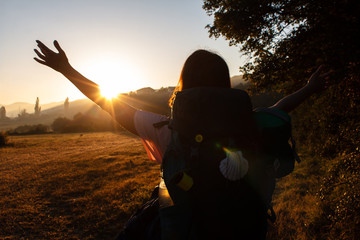 Girl raising arms up and meeting beautiful sunrise on the hills in Spain. Girl hiker meets the...