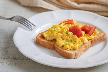 Scrambled eggs with tomato on toasted whole wheat bread.