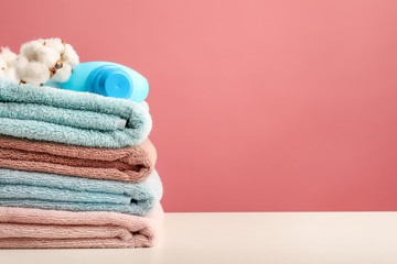 Detergent and cotton branch on stack of bath towels with on pink background