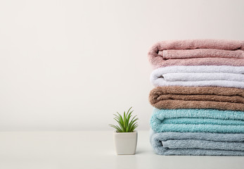 Obraz na płótnie Canvas Stack of bath towels and home plant stand on white background