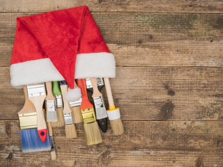 Christmas construction tools on wooden background. Brush in a cap of Santa Claus.