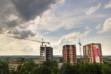 Aerial view of tower lifting crane and concrete frame of tall apartment residential buildings under construction in a city. Urban development and real estate growth concept.