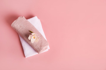 Bath towels and orchid flower on pink background