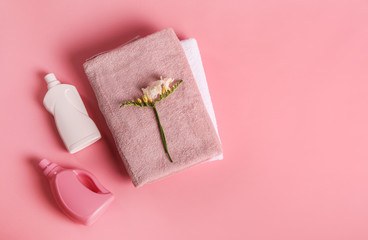Bath towels, detergent and freesia flower on pink background