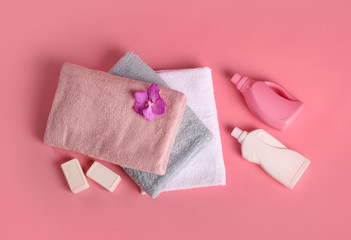 Bath towels, detergents, soap and orchid flower on pink bachground