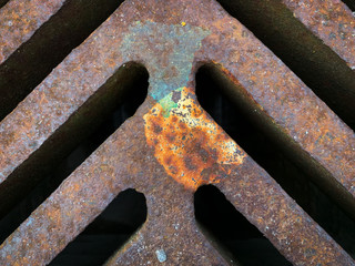 Close up image of an old, rusty steel sewer grate on a road for drainage purposes. Abstract concept, grunge or industrial background, wallpaper or texture.