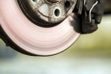 Closeup of braking disc of the vehicle with brake caliper for repair in process of new tire replacement. Car brake repairing in garage.