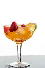 cocktail with ice, orange juice, berries, strawberries, frozen raspberries and a slice of lime