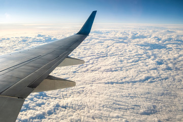 Obraz premium View from airplane on the aircraft white wing flying over cloudy landscape in sunny morning. Air travel and transportation concept.