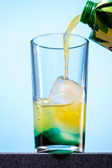 cocktail of orange juice, mint syrup and ice in a direct glass on a blue background
