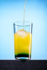 cocktail of orange juice, mint syrup and ice in a direct glass on a blue background