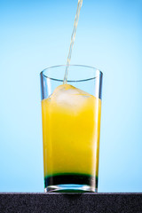 cocktail of orange juice, mint syrup and ice in a direct glass on a blue background