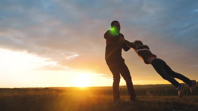 happy family. dad is circling son his a having fun silhouette at sunset. man father and little boy son kid play outdoors dad holds hands this is circling light lifestyle in nature