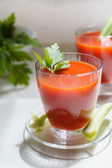 Tomato juice in a glass with celery and parsley leaves on white background. Lifestyle healthy eating concept 