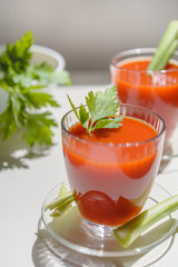Tomato juice in a glass with celery and parsley leaves on white background. Lifestyle healthy eating concept 