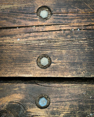 Close up photo of rustic, weathered wooden boards with metal bolts. Textured background, banner or wallpaper.