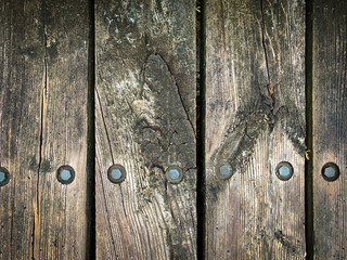 Close up photo of rustic, weathered wooden boards with metal bolts. Textured background, banner or wallpaper.