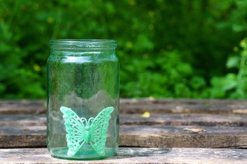 A toy butterfly in an empty glass jar.