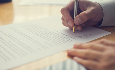 A people signing a document. Hand holding a pen.