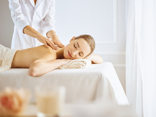 Fototapeta na wymiar Beautiful woman enjoying back massage with closed eyes. Spa treatment concept