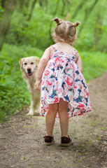 Happy little girl with light dress with dog standing on the forest road. Cute little girl play with a dog, pets day