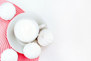 Cup of cappuccino and white zephyr on white and pink background. Top view with copy space