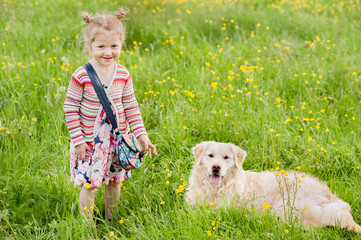 A little blond girl with her pet dog outdooors in park