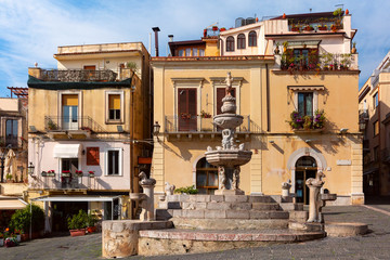 Fototapeta na wymiar Fountain and typical houses with restaurants on the square Piazza Duomo in Taormina on sunny morning, Sicily, Italy