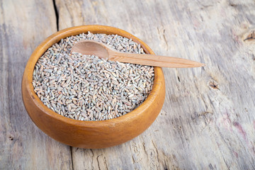 Unpeeled raw oats in a wooden plate on a wooden table
