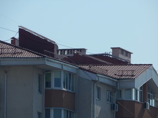 Ventilation pipes on the roof of the house. The roof of the house is made of red metal. 