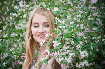 Beautiful young woman posing in Azalea bushes. Blonde in pink flowers. Smiling model