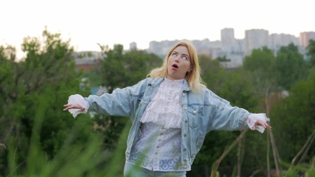 blond girl in a beautiful shirt turned into a zombie and goes against the background of the city there are people