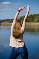 Girl dancing near the lake, sunny weather. A young woman rejoices in life, dances and sings. She has a good mood and a smile on her face.