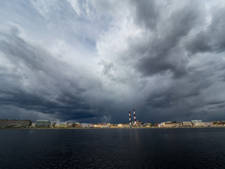 Fototapeta premium Granite embankment of the river with storm clouds over the water. Spring city landscape with a river.
