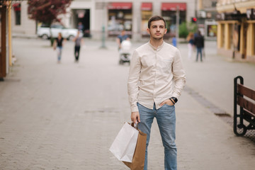 Handsome young man in the city stand with craft package
