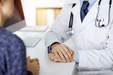 Female doctor and male patient discussing current health examination while sitting in sunny clinic, close-up. Medicine concept