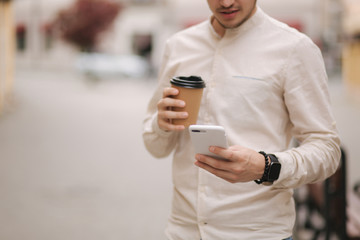 Fototapeta premium Middle selection of man stand in the city with cup of coffee and use phone