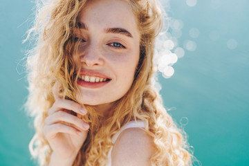 curly blonde smiling broadly with a gentle gaze of blue eyes against the background of sparkling...