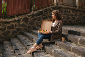 Fototapeta premium Attrative woman open pizza box and eating vegan pizza outdoors