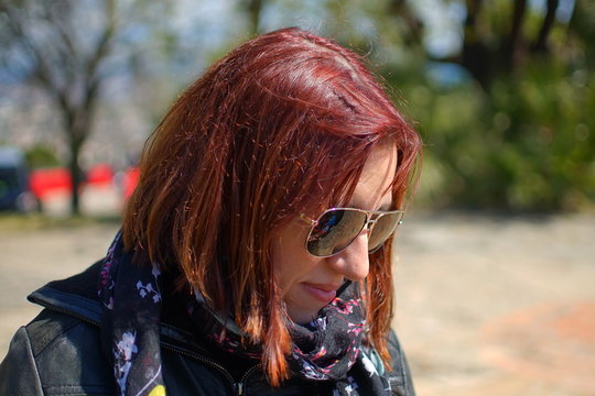 mujer pelirroja mirando al suelo con gafas de sol