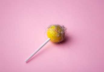 Dirty lollipop on a pink background. Lollipop with hair, dust and dirt on an empty minimal background. Minimal art concept