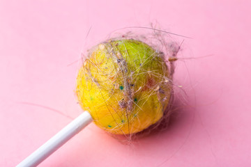 Dirty lollipop on a pink background. Lollipop with hair, dust and dirt on an empty minimal background. Minimal art concept