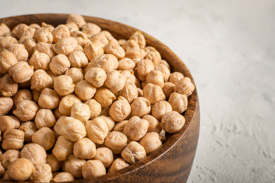 Chickpeas in wooden bowl on white background.