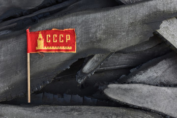 The old small flag of the Soviet Union on burnt boards. symbol of the Soviet Union. burnt past. concept