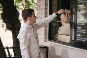 Young man take fresh food from vegan caffe outdoor