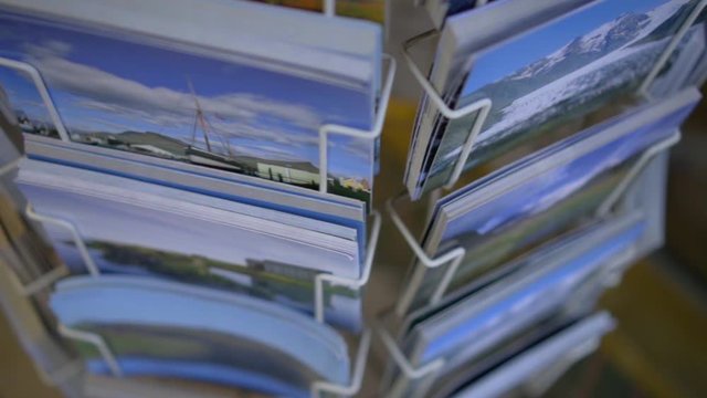 Rack with postcards. Postcards with beautiful country landscapes and animals revolve around